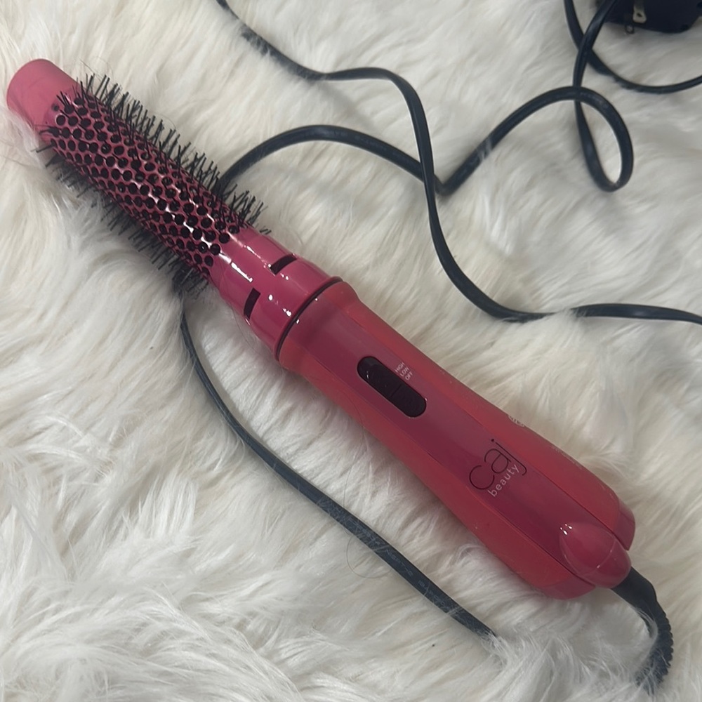 Pink Electric Hair Styling Tool with Cylindrical Barrel and Black Bristles